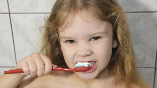 slow girl, baby in the bathroom brushing her teeth with toothpaste