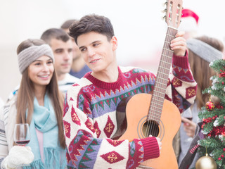 Young man with friends on Christmas,playing guitar