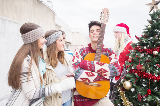 Young man with friends on Christmas,holding guitar - Powered by Adobe