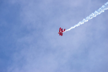 red airplane doing acrobatics in blue sky