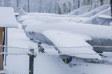 Military aircraft fighter exhibit covered in snow.