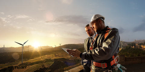 Windmill engineer and businessman planing new ecology project. they standing and looking in tablet.