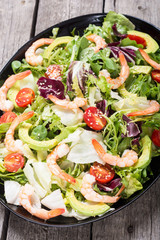 Mix of salad with shrimps , avocado and cherry tomatoes . Healthy food background