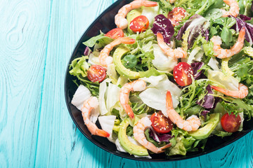 Mix of salad with shrimps , avocado and cherry tomatoes . Healthy food background