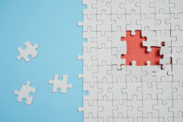 Fragment of a folded white jigsaw puzzle and a pile of uncombed puzzle elements against the...