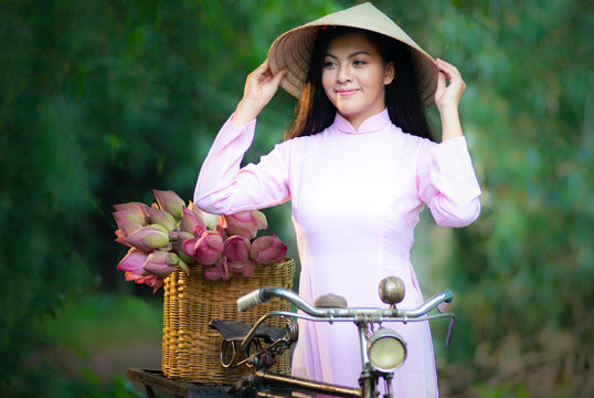 Asian cute girl in  Vietnamese national costume of Vietnam with the beautiful of lotus flower which is indicated as Vietnam's National Flower