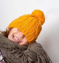 Close up face portrait of toothy smiling young woman wearing knitted hat and scarf. 