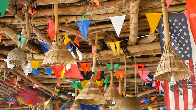 Decorative national flags of different countries hanging on strings in wooden tropical bungalow. Exotic rasta bar interior. Summer beach house on Koh Phangan island, Thailand.