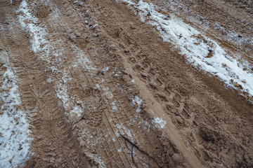 Car Tire Marks on an Empty Field Covered With Snow, Wood in the Background