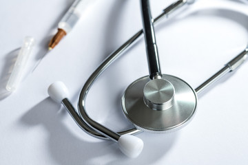 stethoscope on white table with syringe
