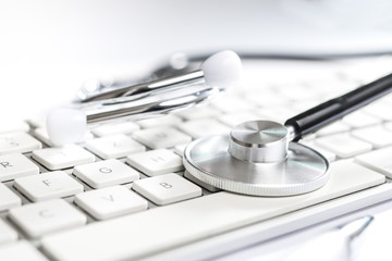 stethoscope on white table with computer keyboard