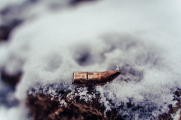 Bent Bullet After Being Shot on The Snowy Sand Background