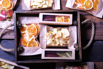 Assorted dried fruits in wooden box, oranges, apples, kiwi, strawberry