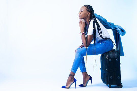 A woman is sitting on a suitcase. Black girl traveler. Moving to another country. Emigration. African girl thinking about emigration. Cheerful look. Tourist. The girl thinks about the future.