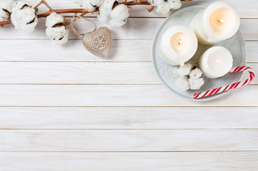 Cotton branch, candles and candy cane on white wooden Background. Close-up, top view. Christmas and New Year background. Copy space