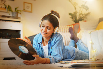 Attractive brunette listening to vinyl records on floor at home