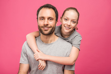 smiling blonde daughter hugging her father, isolated on pink