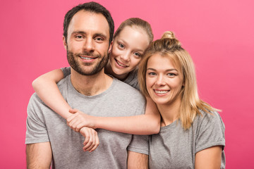smiling daughter hugging her happy parents, isolated on pink
