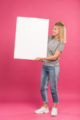 beautiful happy woman posing with empty placard, isolated on pink