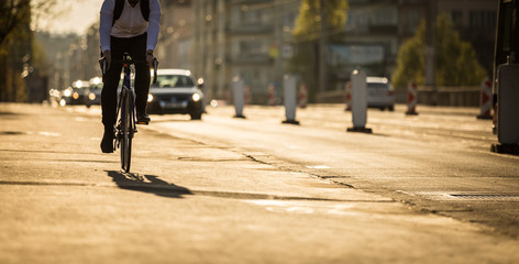 Bikers on a city street in warm evening sunlight - obrazy, fototapety, plakaty
