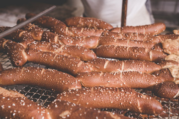 Frisch gebackene Laugenstangen mit Salz auf einem Rost zum abkühlen in der Backstube
