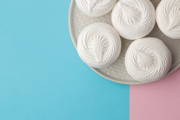 Sweet white marshmallow on a plate on a bright trendy blue and pink background. Sweets. dessert. top view with space for text