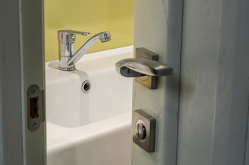 Obraz premium View through the open door to the faucet on the washbasin in the bathroom