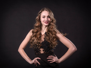 Fototapeta premium Portrait of a smiling young girl in a lace dress on a black background