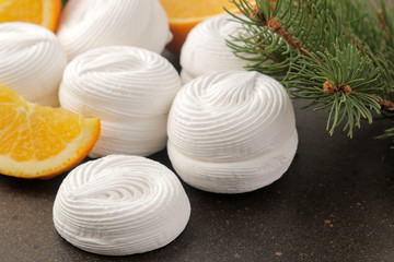 Sweet white marshmallows with orange filling and fresh oranges and a sprig of Christmas trees on a dark background Sweets. dessert.
