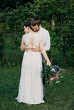 Bride and groom standing on meadow embracing