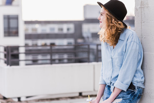 Content young woman wearing hat relaxing on roof terrace