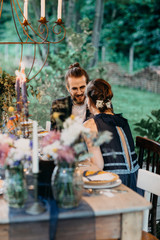 Fototapeta na wymiar Happy bride and groom sitting at festive laid table outdoors