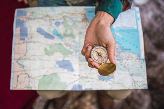 Hand holding compass over map