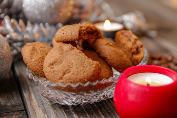 Cookies filled with chocolate, Christmas balls, candles and coffee beans. Close-up on the old rustic wooden table