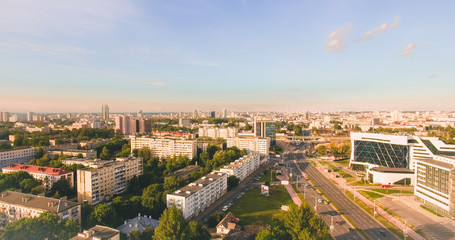 Aerial drone shoot with top view near Renaissance Hotel in Minsk, Belarus. Beauty morning sunrise with modern architecture, road, cars traffic and trees, blue sky. Sun shining