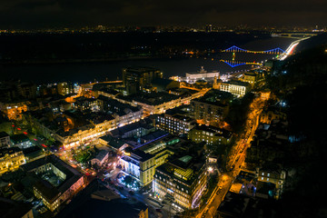 Fototapeta na wymiar Urban landscape at night. Lights of Podil in Kiev. Colorful bridge on the background