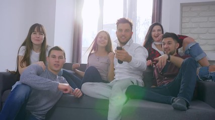football fans in backlight, running friends jump on the sofa and turn on the TV to watch the match and then celebrating success with high five and excited gestures - Powered by Adobe