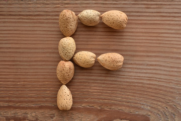 the letter F shaped with almonds on wood