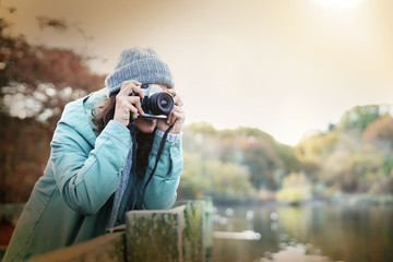 Attractive young brunette taking photos outdoors in fall