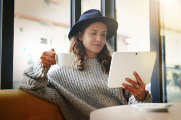 Attractive brunette with tablet in modern cafe