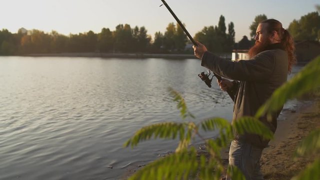 Fisherman is fishing with a fishing rod. Fisher raises and lowers spinning.