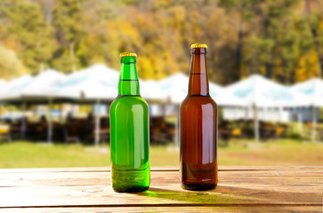 green and brown beer bottle on table against blurred background of summer playground