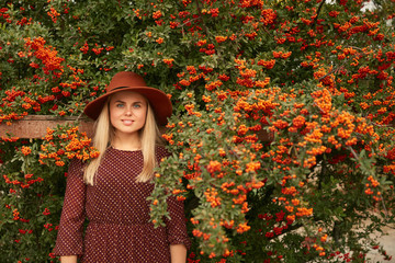 Fototapeta na wymiar Beautiful Smiling Woman In Hat And Dress Near Rowan Tree