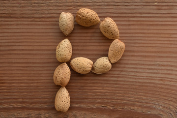 the letter P shaped with almonds on wood