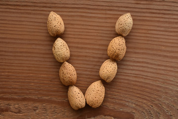 the letter V shaped with almonds on wood
