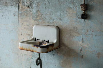 Old rusted sink with broken faucets and light switch in Alcatraz prison