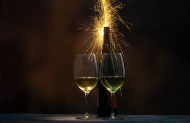 A spark of fireworks became the background for a bottle of wine and two glasses filled with wine.