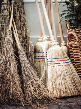 Old brooms stand against a wall