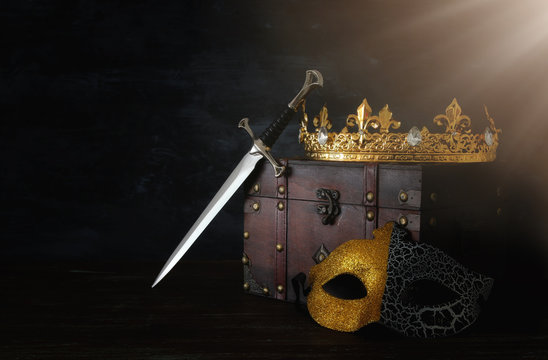 low key image of beautiful queen/king crown, mysterious mask and sword. fantasy medieval period.