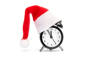 Alarm clock with Santa's hat on white.